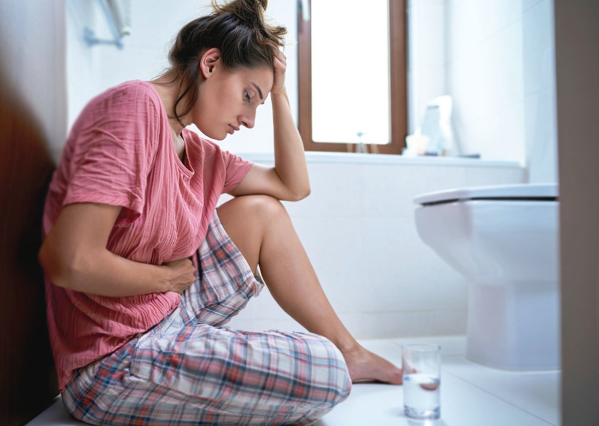 Девушка грустно сидит над тарелкой еды